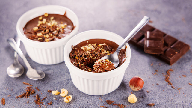 chocolate mousse dessert with crushed hazelnuts in ramekin spoon dark chocolate bar close up