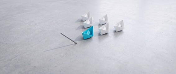 Fototapeta premium Blue paper boat leading a group of white origami boats on a grey stone surface, representing leadership, vision, and a shift in perspective for business success and strategic innovation.