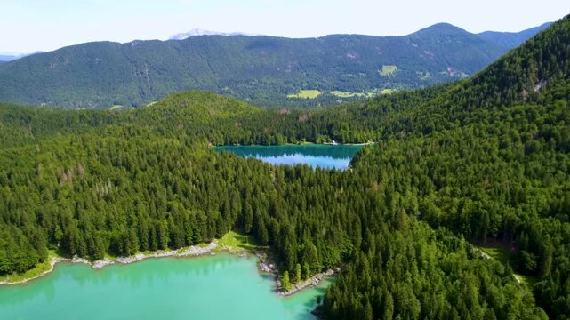 Stunning aerial view flying over the two Fusine lakes, Lago di Fusine Superiore and Lago di Fusine Inferiore in the Julian Alps in northeastern Italy during summer.