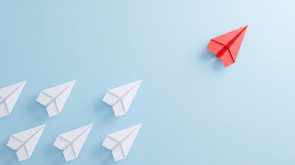 Fototapeta premium Top down overhead view of a single red paper plane flying in a different direction from a group of white paper planes on blue background representing leadership, innovation, and business vision.
