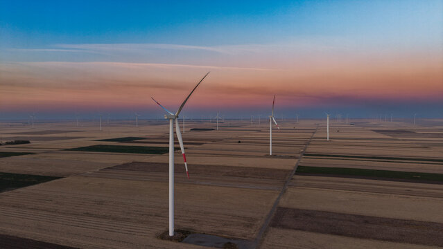 Aerial view of wind turbines in a vast agricultural field during sunset in Kovacica, Vojvodina, Serbia.