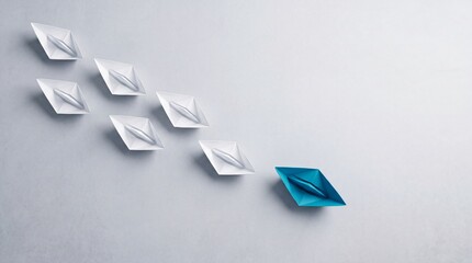 Fototapeta premium Leadership and Business Success Concept with a Blue Paper Boat Leading White Ones in a Top Down View, Symbolizing Innovation, Uniqueness, and Guiding a Team Towards a Goal on a Gray Background
