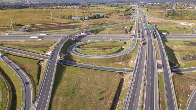 Hyperlapse aerial view of highway interchange, modern road infrastructure and heavy traffic flow with cars and trucks on expressway