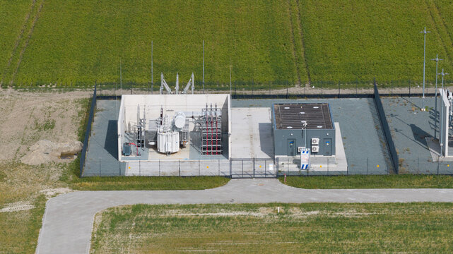 Aerial view of the Westermeerdijk electrical substation featuring a transformer and control building within a fenced enclosure surrounded by green fields in Espel, Flevoland, Netherlands.