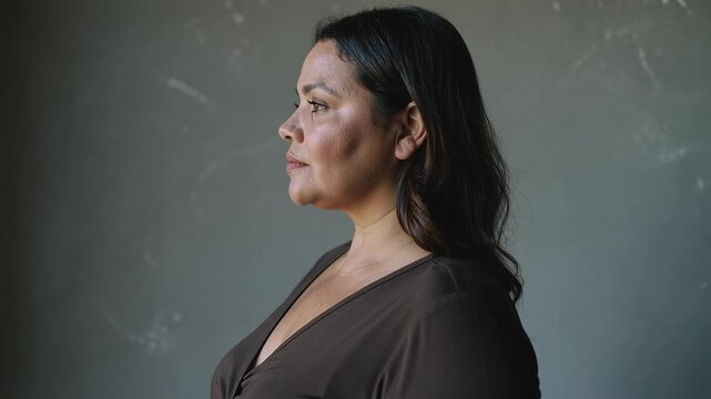 Turning after director cue, woman rotating right in studio, showing brown V-neck top and necklace