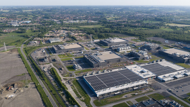 Aerial view of the Google data center featuring large industrial buildings with solar panels on rooftops, surrounded by green fields and infrastructure in Saint-Ghislain, Region wallonne, Belgium.