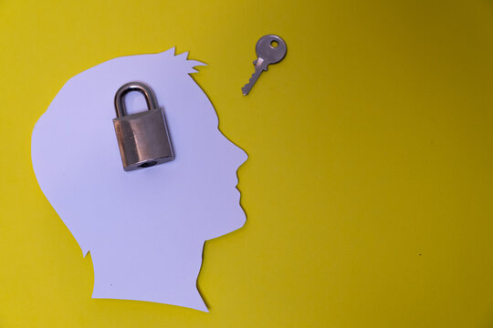 Conceptual composition representing the protection of privacy and personal security through the silhouette of a human head, a closed lock, and a separate key. Concept of confidentiality, locking, info
