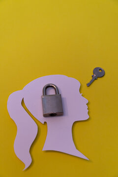 Conceptual composition with the silhouette of a human profile, a closed padlock placed over the head, and a separate key, representing privacy, protection of thoughts, personal security, access contro