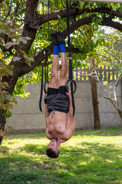 Man Hanging Upside Down on Gymnastic Rings in Backyard