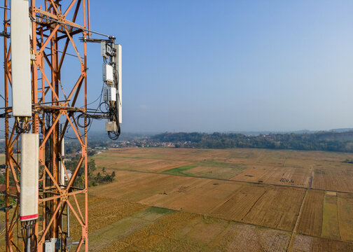 Aerial view of a telecommunications tower overlooking vast agricultural fields and rural landscape in Patikraja, Central Java, Indonesia.