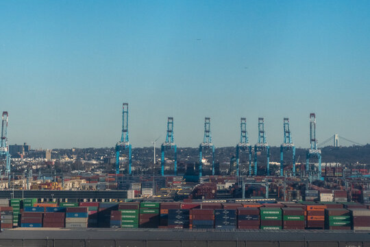 Port of Newark, New Jersey, USA - February 4, 2024 - Aerial view of ship-to-shore gantry cranes and stacked shipping containers from Maersk, Evergreen, COSCO, and CMA CGM with the Verrazzano-Narrows
