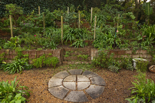Circular stone feature showing central disc and wedge slabs sitting in gravel backyard