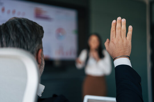 Businessperson raising hand asking question in meeting