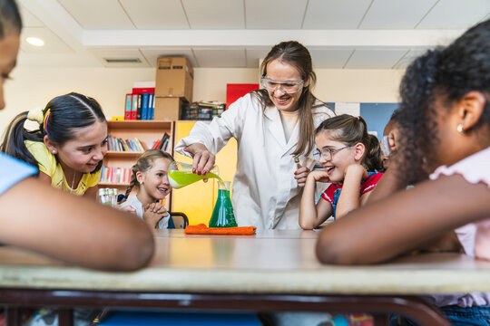 Teacher and multi ethnic children learning chemistry with flasks and colorful liquids during a fun science lesson at school