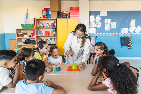 Teacher and multi ethnic students performing a science experiment with colorful liquids in beakers, exploring chemistry concepts