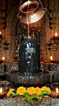 Shiva Lingam Abhishekam with Water Dripping from Copper Pot - A sacred Shiva Linga rests within a stone sanctum, receiving an abhishekam ritual.