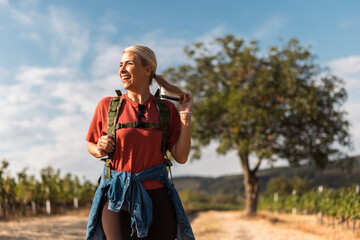 Fototapeta premium Happy woman enjoying a hike in vineyard landscape on sunny day