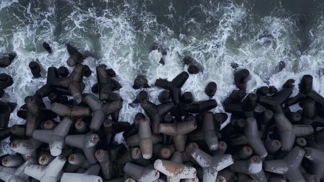 Top Down Aerial View of Ocean Waves Crashing on Concrete Breakwater