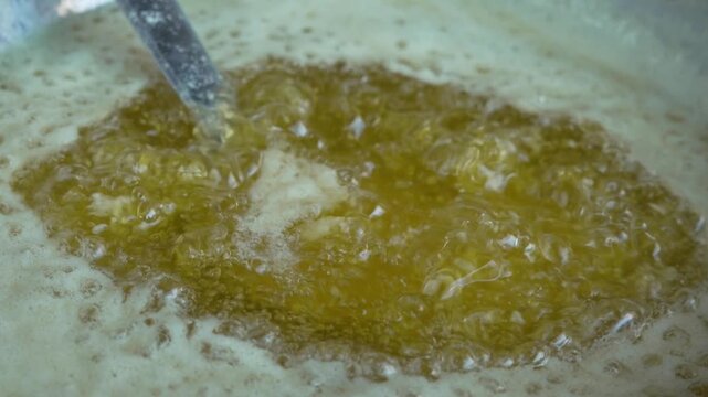 Pure cow ghee boiling in a pan with bubbles being stirred