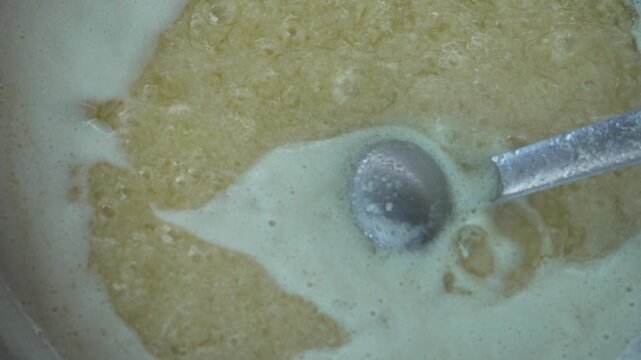 Making ghee by boiling butter in a pan with bubbles and foam