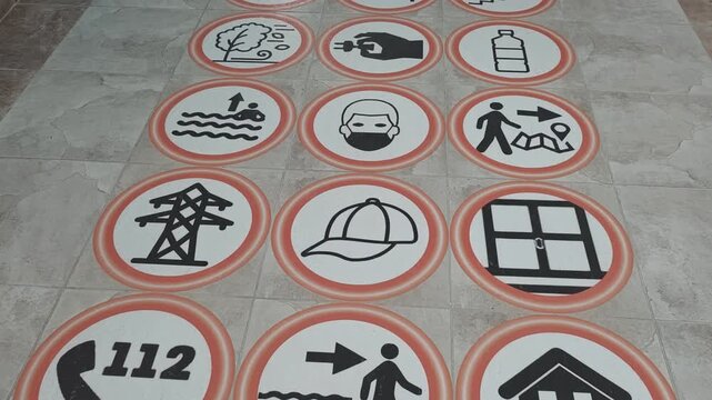 Collection of circular safety signs on the floor. Pictograms depicting evacuation routes, emergency actions, and survival guidelines