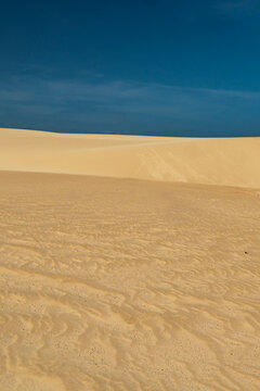 Layered sand dunes under a blue sky