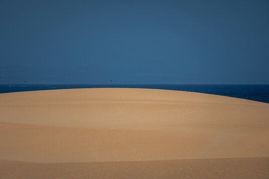 Dark dune ridge under a blue evening sky