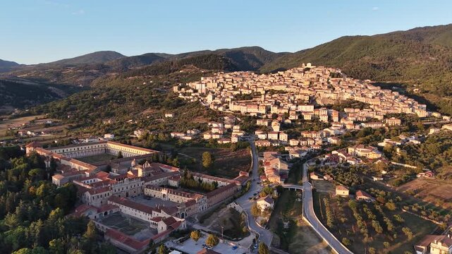 Aerial view of the Certosa di San Lorenzo and the hilltop village of Padula at sunset in the Vallo di Diano, Salerno, Italy