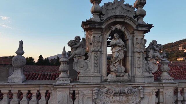 Baroque sculpture of the Virgin Mary flanked by angels on the facade of the Charterhouse of Padula at sunset, Salerno, Italy