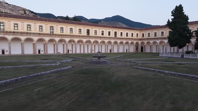 The Great Cloister of the Certosa di San Lorenzo in Padula with its marble fountain and long arcades at dusk, Salerno, Campania, Italy