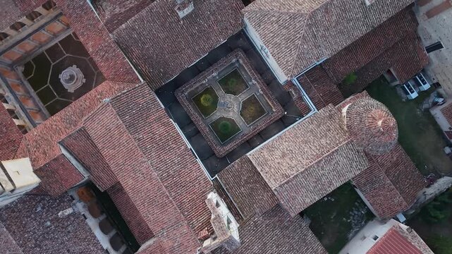 Top down aerial view of the terracotta rooftops and garden courtyards of the Certosa di San Lorenzo monastery, Padula, Campania, Italy