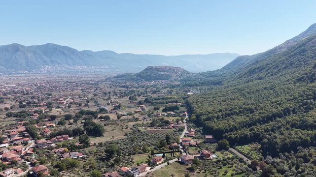 Aerial view over olive groves and country houses on the edge of the Vallo di Diano plain with the hilltop town of Teggiano in the distance, Salerno, Italy