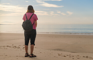 Senior female traveler with backpack standing on Cadiz beach sunset © Paolo Corazza