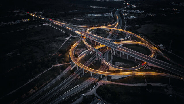 Aerial view of a circular highway interchange at night with interchange circular junction transportation infrastructure illumination expressway landscape perspective cityscape engineering