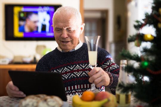 Cheerful senior man making video call on tablet at Christmas