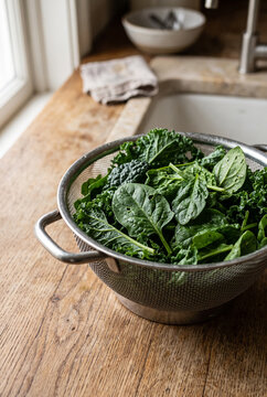 Leafy spinach and kale in a metal colander