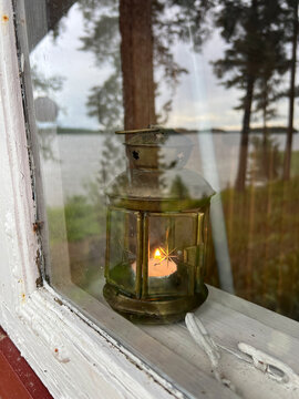 Laterne in Sauna bei altem Fenster mit See, Finnland