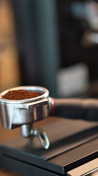 Vertical 4K close-up footage of ground coffee in portafilter on digital scale for espresso preparation in coffee shop cafe.