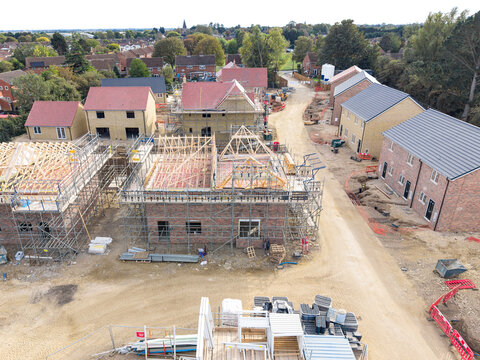 Interesting drone view of partially built private and affordable homes on a British housing estate. On the right is a row on semi detached houses waiting for draining to be installed.