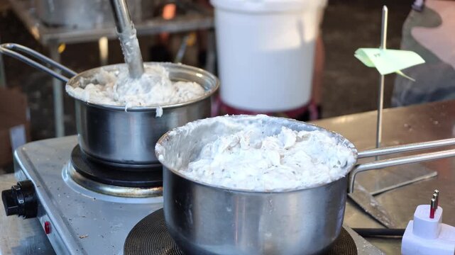 Borlengo batter bubbling in pots, blending ingredients for this traditional savory crepe dish from Emilia-Romagna in Italy, served with filling of Parmigiano Reggiano cheese and lard. SLOW MOTION: