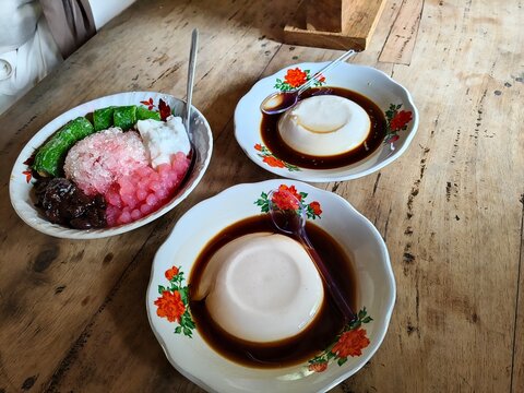 Traditional Indonesian Dessert, Es Pisang Ijo and Bubur Sumsum Pudding, Sweet Southeast Asian Street Food Delicacy on Wooden Table