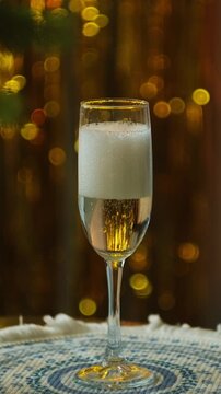 Vertical video. New year eve party. Pouring champagne or white sparkling wine into a glass