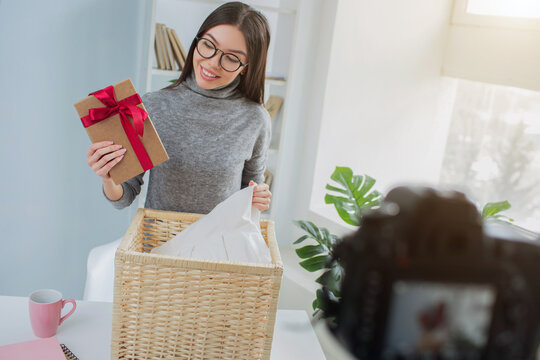 Girl has found a present in the basket with laundry. She looks surprised and happy. The blogger is recording her reaction on video.