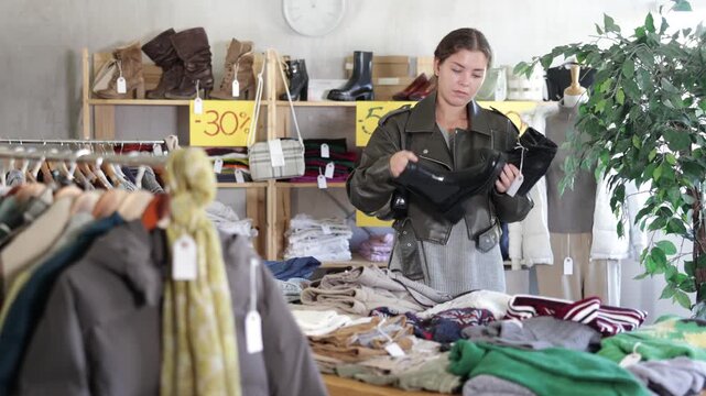 In sales area of store, woman customer chooses boots. Creating capsule wardrobe, branded clothing at affordable prices. Modern urban fashion, casual practical clothes 