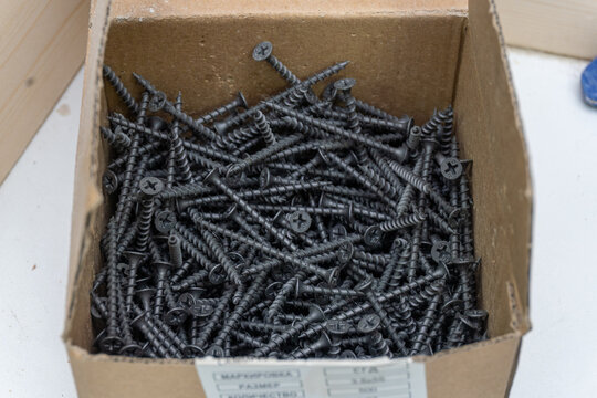 Black self tapping wood screws in cardboard box close up