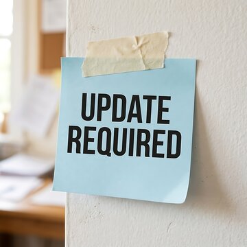 A light blue adhesive note with the text update required taped to a white wall