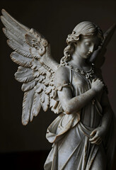 Fototapeta premium Spirituality and mourning, marble angel statue with wings in a peaceful pose for funeral services, religious art and afterlife reflection in a dark room