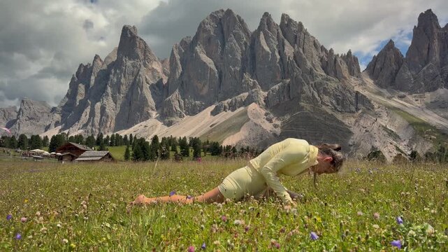 Woman Practicing Upward Dog Yoga near Wooden Huts in the Dolomites