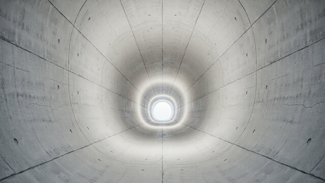 Perspective view looking through a long grey concrete tunnel towards a bright exit with concrete perspective industrial structure architecture interior corridor underground brutalist symmetry