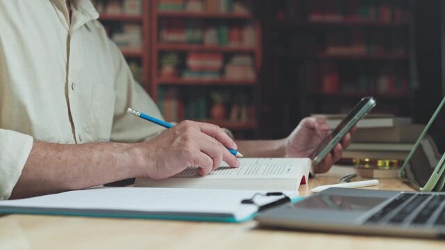 Focused adult conducts research across academic sources, balance intensive research routines with mobile checks as digital research expands learning inside quiet library.